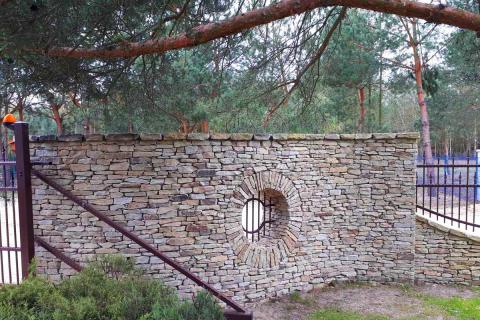mur z okrągły oknem oklejony łupkiem elewacyjnym ciętym granit
